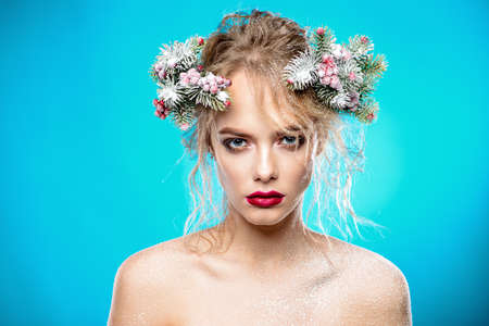Portrait of a beautiful young woman with christmas tree in hairstyle and holiday make-up over blue background. Beauty, fashion.の写真素材