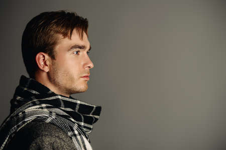 Male beauty, fashion. Portrait of a handsome man wearing coat and scarf. Seasonal clothes collection.の写真素材