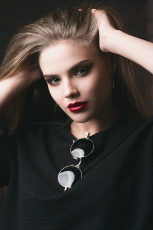 Portrait of an attractive girl with bright makeup and red lips. Styling for long hair. Modern youth...