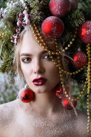 Portrait of a beautiful young woman with christmas tree in hairstyle decorated with beads and balls. Holiday make-up. Beauty, fashion.の写真素材