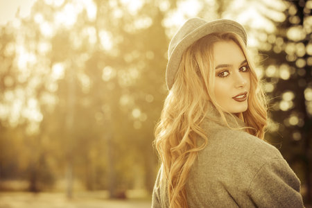 Beautiful fashion model posing in the autumn park. Autumn seasonal fashion.