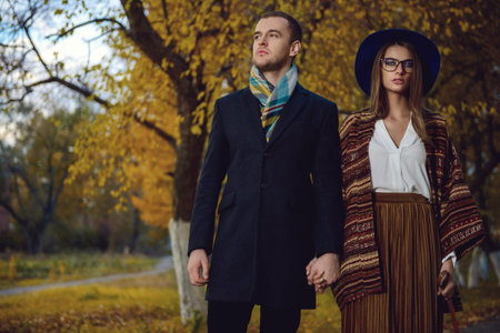 Portrait of a beautiful young people walking in the autumn park. Autumn fashion. 