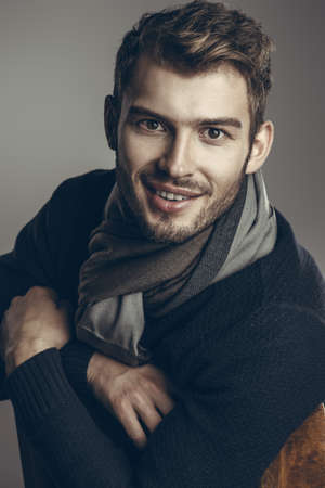 Handsome young man in scarf and sweater. Studio portrait. Autumn and winter clothing. Male fashion.の写真素材