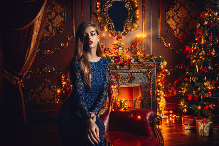 Magical Christmas night. Beautiful woman in evening dress celebrates Christmas in luxurious...