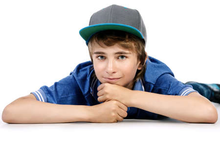 Portrait of a smiling teenage boy lying on a floor. Studio shot. Teen fashion. Isolated over white.の写真素材