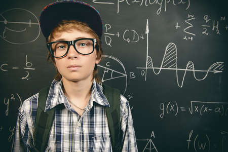 Education, high school, college. Portrait of a student boy standing by a school blackboard. の写真素材