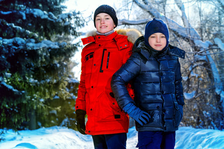 Two happy boys playing together outdoor on a sunny winter day. Snowfall. Winter clothes. Winter activity.の写真素材