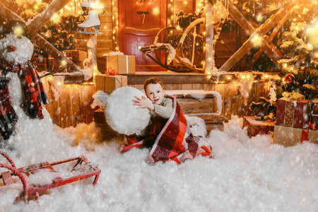 Cute child boy sculpts a snowman near his house decorated for Christmas. Merry Christmas and Happy New Year.の写真素材