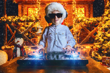 Little boy-DJ is having a party near the house of Santa Claus decorated with lights. Christmas party concept.の写真素材