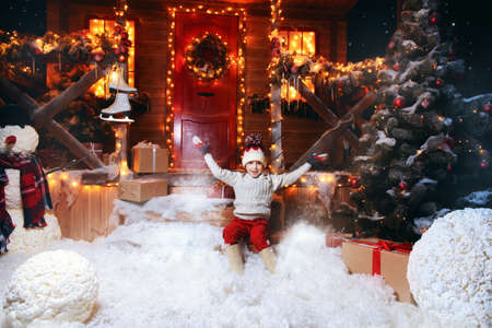 Cute child boy is sitting near his house decorated for Christmas. Merry Christmas and Happy New Year.の写真素材