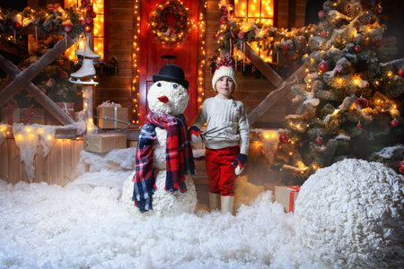 Five-year-old boy made a snowman in the courtyard of a festively decorated house. Merry Christmas...