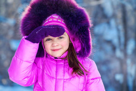Joyful child girl playing outdoor on a sunny winter day. Winter clothes for kids.の写真素材