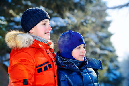 Two happy boys playing together outdoor on a sunny winter day. Snowfall. Winter clothes. Winter activity.の写真素材
