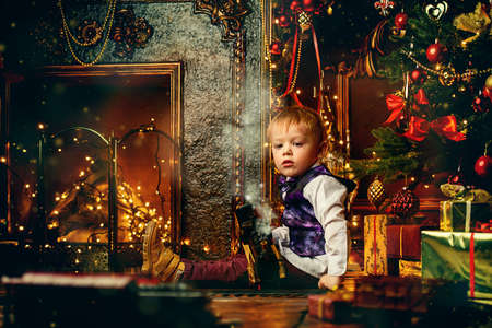 Cute three-year-old boy playing with a toy railway near the Christmas tree. Christmas night. Christmas decoration.の写真素材