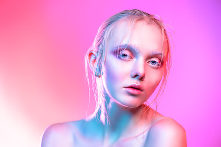 Beauty concept. Beautiful blonde girl with natural makeup and shiny healthy skin over pink...