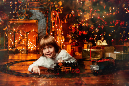 Cute five-year-old boy playing with a toy railway near the Christmas tree. Christmas night....