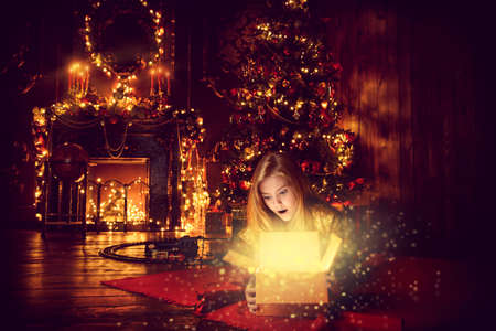 Pretty nine year old girl opens a gift box and surprises. Luxurious apartments decorated for Christmas. Merry Christmas and Happy New Year.の写真素材