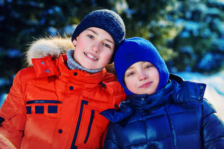 Two happy boys playing together outdoor on a sunny winter day. Snowfall. Winter clothes. Winter activity.の写真素材