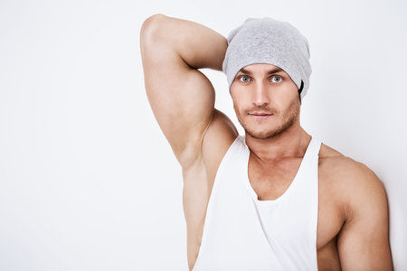Portrait of a handsome athletic man posing in casual clothes in white room. Health and sports....
