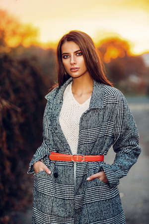 Attractive fashionable woman posing in the autumn park on a sunset. Autumn seasonal fashion.の写真素材