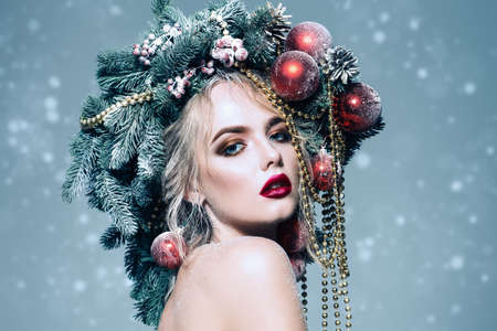 Portrait of a beautiful young woman with christmas tree in hairstyle decorated with beads and balls. Holiday make-up. Beauty, fashion.の写真素材