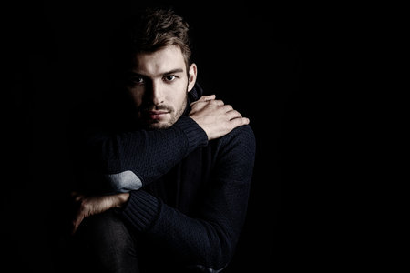 Handsome young man in scarf and sweater. Studio portrait. Autumn and winter clothing. Male fashion.