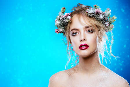 Portrait of a beautiful young woman with christmas tree in hairstyle and holiday make-up over blue background. Beauty, fashion.の写真素材