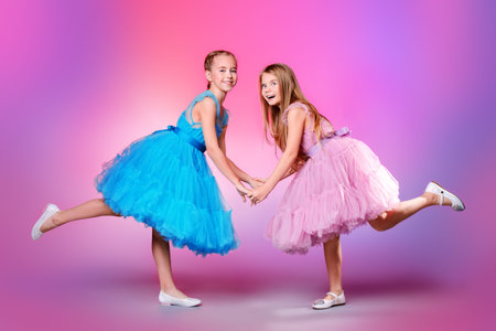 Two pretty little girls dressed in beautiful festive dresses. Kid's fashion concept.