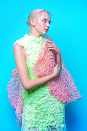 Fashion shot of a beautiful female model posing in designer clothes collection over blue background....