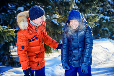 Two happy boys playing together outdoor on a sunny winter day. Snowfall. Winter clothes. Winter activity.の写真素材