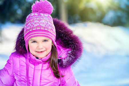 Joyful child girl playing outdoor on a sunny winter day. Winter clothes for kids.の写真素材