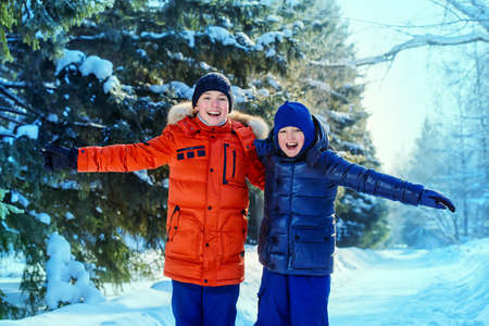 Two happy boys playing together outdoor on a sunny winter day. Snowfall. Winter clothes. Winter activity.の写真素材