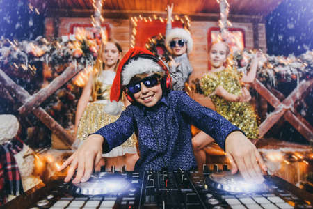 Group of happy children is having a party near the house of Santa Claus decorated with lights. Christmas party concept.の写真素材