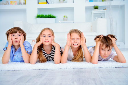Four funny children lie on the floor at home and laugh. Child concept.