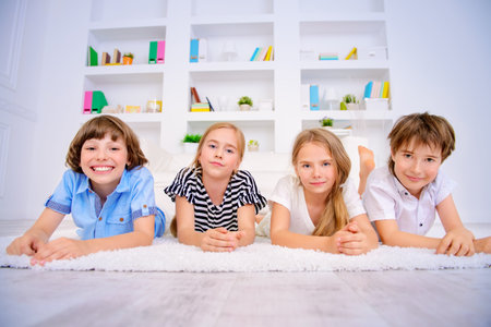 Four funny children lie on the floor at home and laugh. Child concept.の写真素材