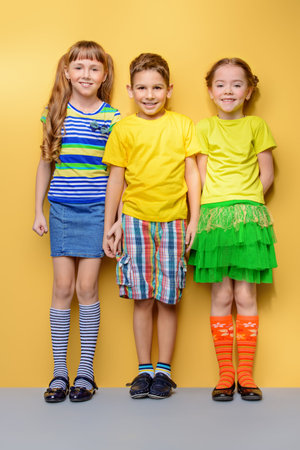 Happy joyful children having fun together. Children's fashion. Education. Happiness, activity and child concept. Bright yellow background.の写真素材