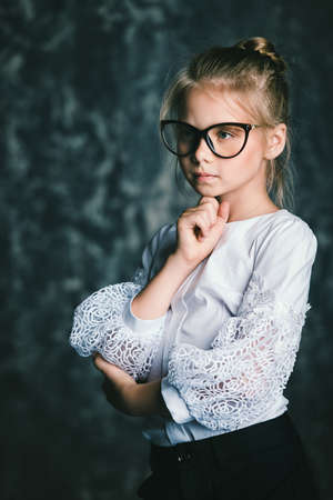 Portrait of a serious pensive schoolgirl in big glasses. Educational concept.の写真素材