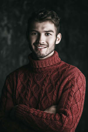 Portrait of a handsome smiling young man in a warm sweater. Autumn, winter clothes. Male beauty, fashion.の写真素材