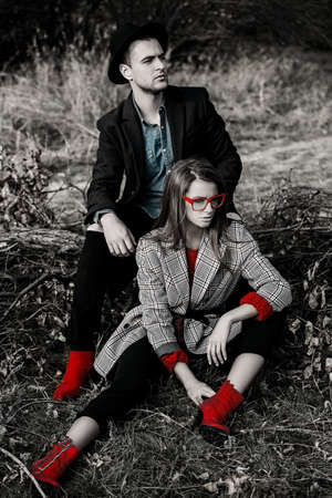 Autumn fashion. Beautiful fashionable couple on yellowed autumn grass and leaves.の写真素材