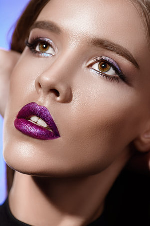 Close-up portrait of an attractive girl with bright makeup and violet lips. Beauty, fashion....