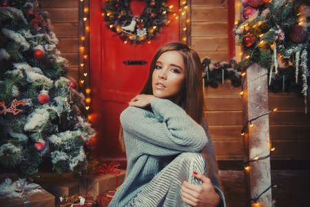 Happy girl in a warm winter clothes poses near the house decorated for Christmas. Time for miracles. Merry Christmas and Happy New Year.の写真素材
