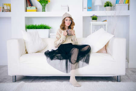 Trendy cute teen girl relaxing at home and drinking coffee. Youth style.の写真素材