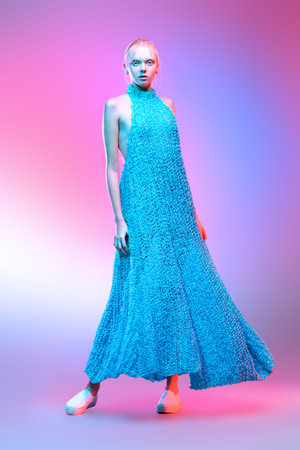 Vogue shot of a female model posing at studio girl in a long knitted dress. Fashion collection. Full...