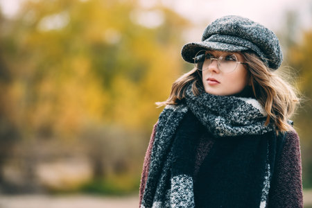 Cute teen girl in modern clothes posing outdoor. Warm autumn day. Seasonal autumn and winter fashion.の写真素材