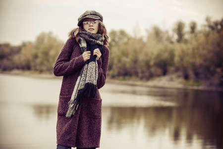 Cute teen girl in modern clothes posing outdoor. Warm autumn day. Seasonal autumn and winter fashion.の写真素材