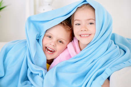 Two happy children playing together at home. Brother and sister under the blanket. Family concept.の写真素材