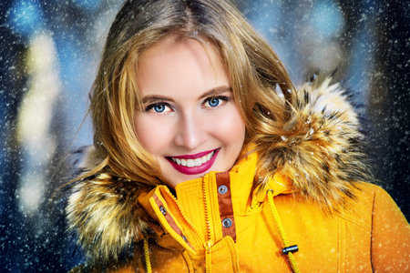 Girl walking in forest on winter day. Fashion shot. Down Jackets.