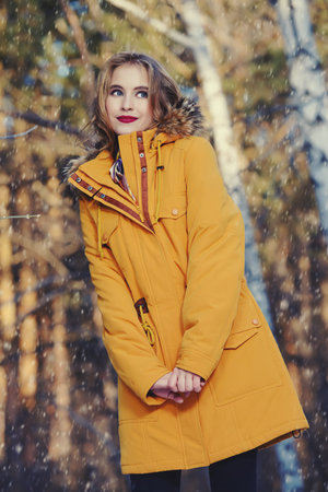 Girl walking in forest on winter day. Fashion shot. Down Jackets.