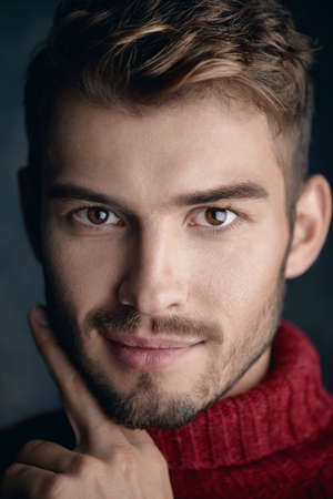 Portrait of a handsome smiling young man in a warm sweater. Autumn, winter clothes. Male beauty, fashion.の写真素材