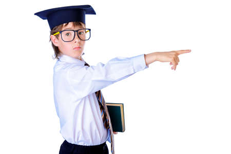 Portrait of a serious student boy in academic hat with a book. Educational concept. Isolated over white.の写真素材
